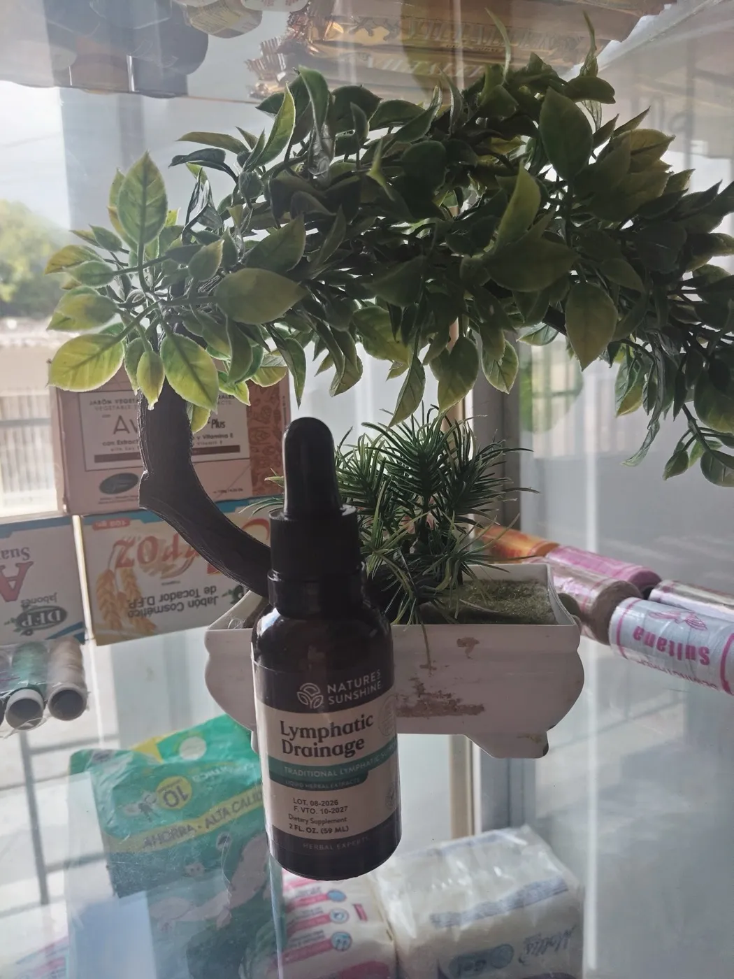Frasco gotero de extracto herbal para drenaje linfático sobre la vitrina de la tienda